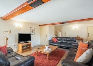 A living room with a television, leather sofas, a coffee table, and a red rug. - 1 bedroom accommodation in Beverley (Beverley)