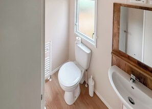 A small, clean bathroom with a toilet, a sink, and a mirror. - 2 bedroom accommodation in Stamford Bridge, York (Stamford Bridge, York)