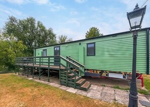 A green mobile home with a staircase leading to the entrance, a small porch, and a street lamp. - 2 bedroom accommodation in Stamford Bridge, York (Stamford Bridge, York)