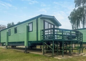 A green mobile home with a balcony and a small attached structure. - 2 bedroom accommodation in Stamford Bridge, York (Stamford Bridge, York)