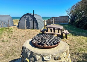 Un camping amb una barbacoa, taula de pícnic i tendes.