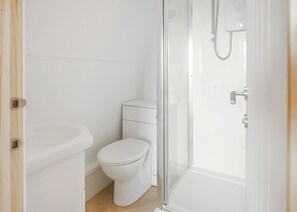 A bathroom with a toilet, sink, and glass-enclosed shower. - 0 bedroom accommodation in Hemsby (Hemsby)