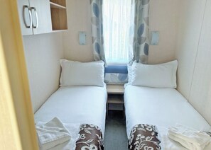 A compact room with two single beds, a small table, and a window with curtains. - 2 bedroom accommodation in Cannock Chase (Cannock Chase)