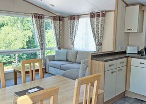 A compact living space with a sofa, dining table, chairs, and a kitchenette. - 2 bedroom accommodation in Cannock Chase (Cannock Chase)
