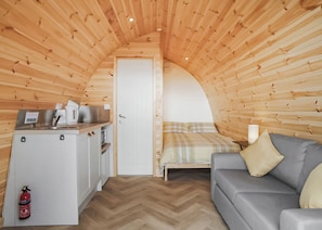 Ein kleines Zimmer mit Küchenzeile, einem Bett und einer Schlafcouch.