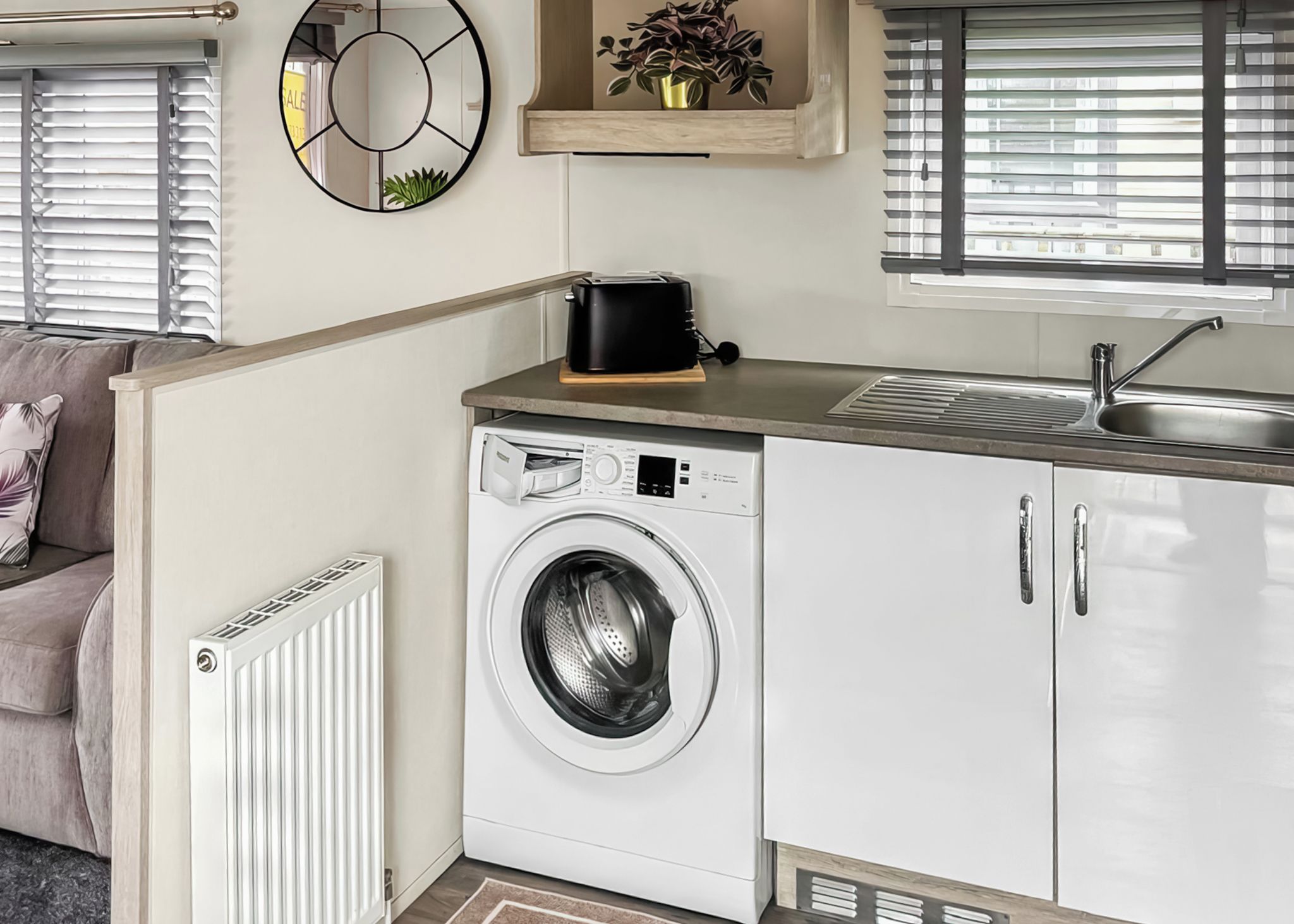 A compact kitchen with a built-in washing machine, a toaster, and a sink.