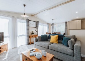 Ein modernes Wohnzimmer mit einem grauen Sofa, einem Holztisch und einem Fernseher.