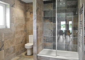 Een badkamer met een douche, toilet en een glazen deur naar een terras.