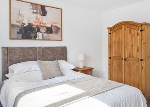 A bedroom with a bed, a nightstand, a lamp, a wooden wardrobe, and a painting on the wall. - 1 bedroom accommodation in Hatfield (Hatfield)