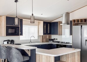 A modern kitchen with a central island, stainless steel appliances, and a pendant light. - Signature Plus 2 Bedroom Lodge Hot Tub (Anstruther)