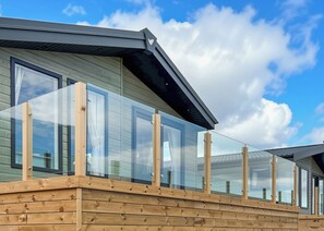 A modern building with large windows and a wooden deck. - Signature Plus 2 Bedroom Lodge Hot Tub (Anstruther)