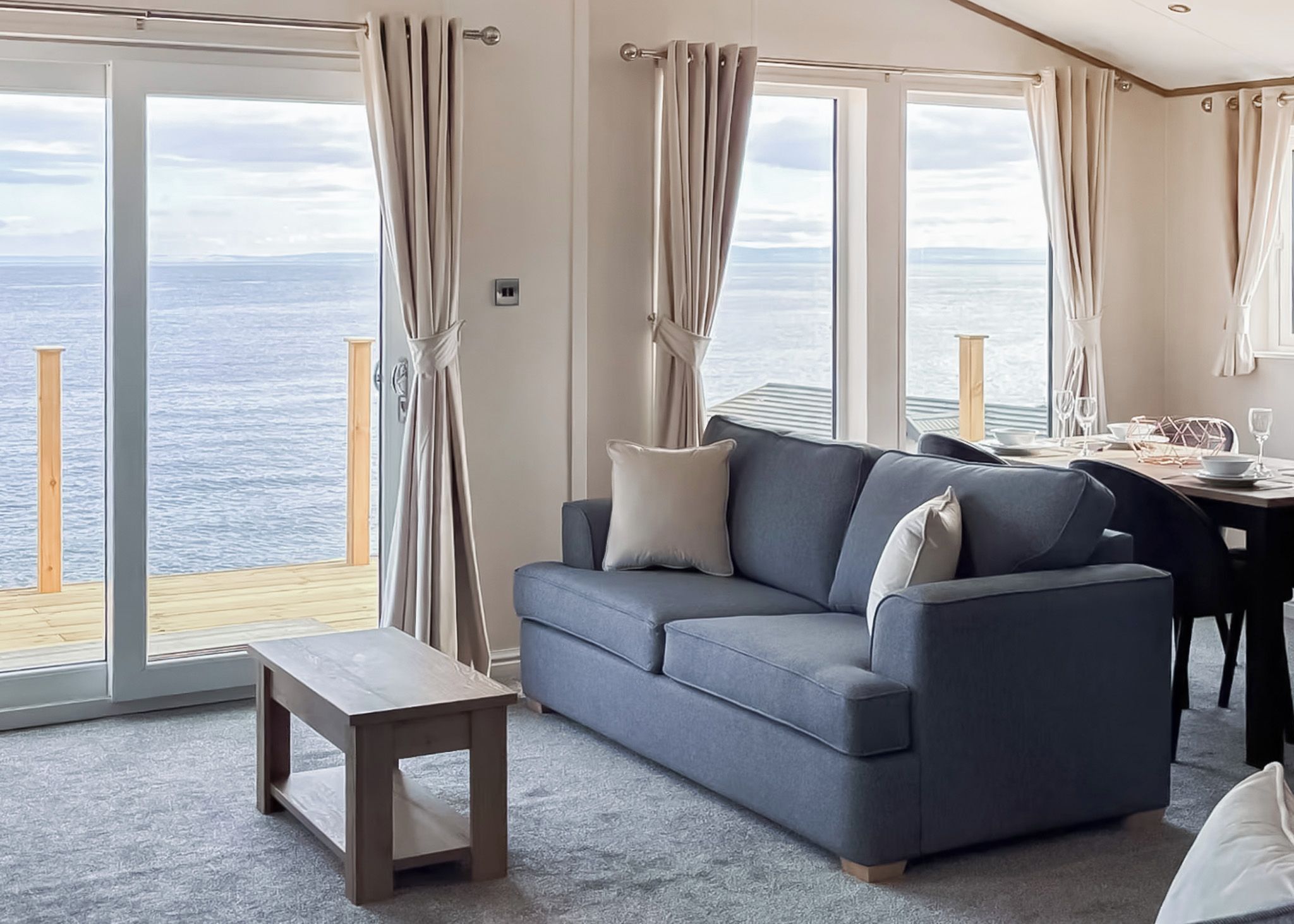 Una sala de estar con sofá, una mesita y vista al mar a través de amplios ventanales.