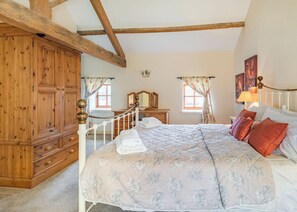 A bedroom with a large bed, wooden wardrobe, and a mirror. - The Dairy is a charming one-bedroom barn conversion at High Farm Holiday Park. (Beverley)