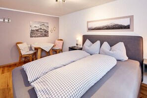 A bedroom with a large bed, a desk, and chairs. There are two wall-mounted picture frames. - Holiday apartment Graseck (Garmisch-Partenkirchen)