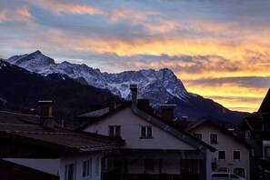 Eine Bergkette mit einer Stadt im Vordergrund, welche traditionelle Architektur und einen klaren Himmel zeigt.