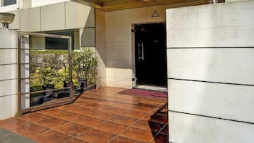 Une entrée moderne avec une porte en verre, des plantes en pot et un sol carrelé.