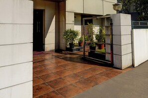 Un patio con piso de baldosas, plantas en macetas y una reja metálica.