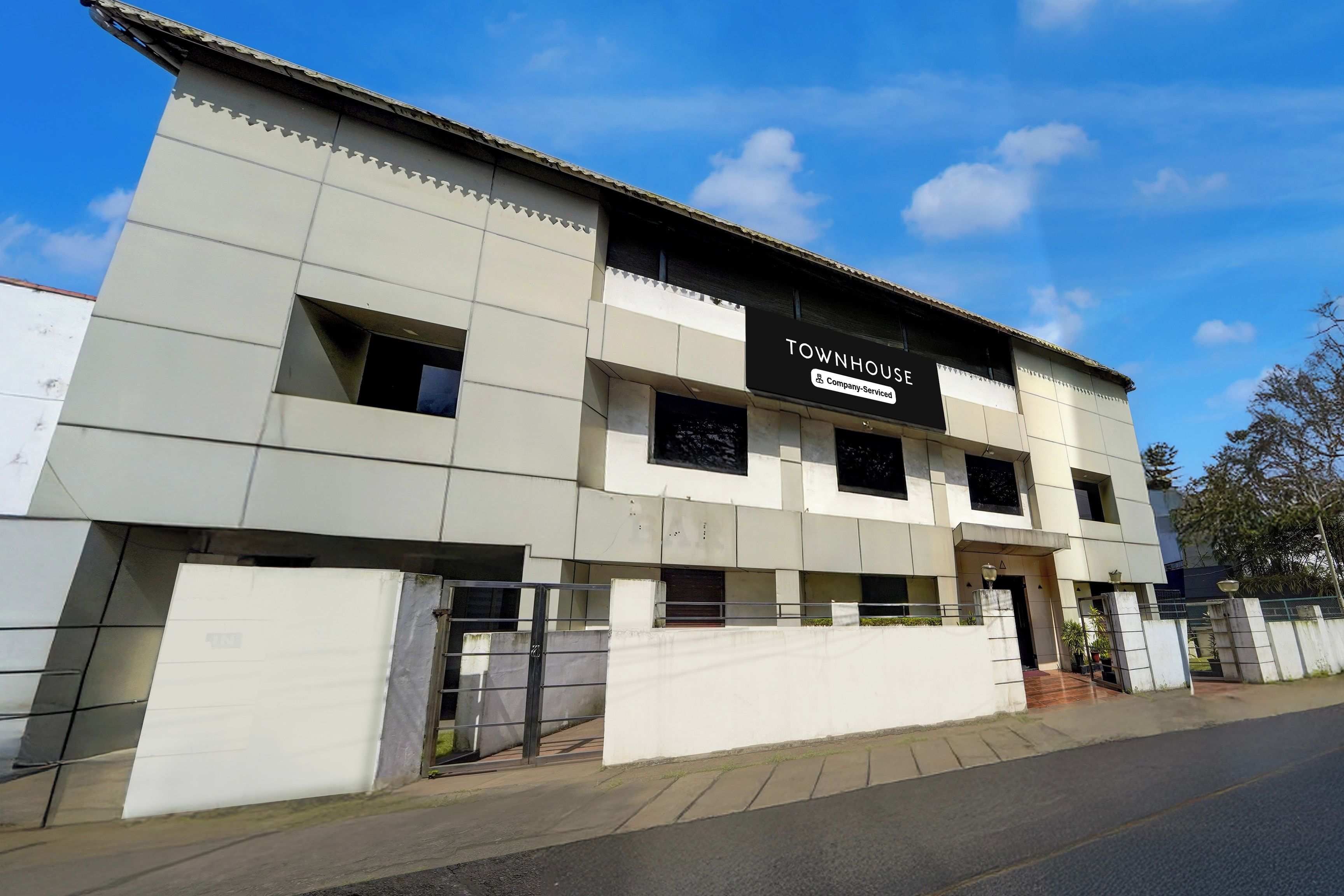 Un immeuble moderne avec une enseigne indiquant qu’il s’agit d’une maison de ville gérée par une entreprise de gestion immobilière.