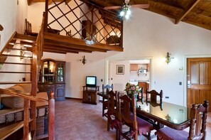 A wooden staircase leading to a loft area with a ceiling fan, a dining table with chairs, and a television in the background. - Las Cuatro Estaciones (Carilo)