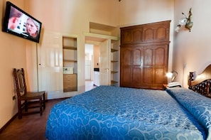 Une chambre à coucher avec un lit, une télévision, une armoire et une chaise.