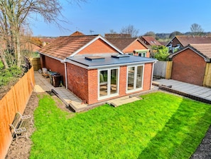 A small brick house with a tiled roof, a fenced backyard, and a grassy lawn. - Finest Retreats | Charnwood Forest Lodge (Shepshed)