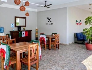 A dining area with wooden tables and chairs, a ceiling fan, and a wall-mounted sign. - Hotel Balxiba, Centro Playa del Carmen (Playa del Carmen)