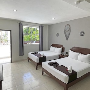 Habitació d'hotel amb dos llits, una finestra amb cortines, una paret amb elements decoratius i un terra solcat.