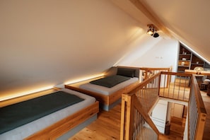 A loft bedroom with two sleeping areas, a wooden staircase, and a sloped ceiling. - Holiday apartment with 1 bedroom (Eichstetten)
