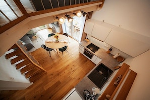 Cozinha moderna com área de refeições, piso de madeira e escada.