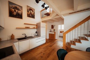 A modern kitchen with white cabinetry, a wooden countertop, and a built-in oven. There is a wooden staircase leading to an upper level. - Holiday apartment with 1 bedroom (Eichstetten)