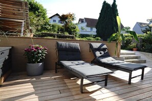 Una terraza de madera con dos sillones y una planta en maceta.