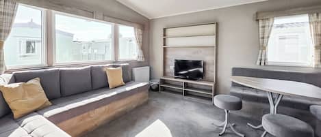Una sala moderna con un sofá, un televisor y un comedor.