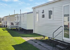 A row of mobile homes with a grassy lawn and a paved walkway. - Brand New Luxury Silver Caravan sleeps 8 (Ingoldmells, Skegness)