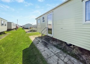 A row of mobile homes with a grassy lawn and a paved walkway. - Brand New Luxury Silver Caravan (Chapel St Leonards)