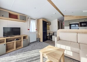 Ein modernes Wohnzimmer mit Flachbildfernseher, Holzmöbeln, einer Couch und einem kleinen Holztisch.