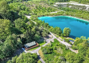 A secluded lakeside property with a wooden cabin, a paved walkway, and lush greenery. - Hilltop Safari Lodge (Halling)