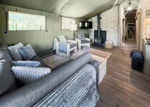 A cozy living room with a sofa, armchairs, a flat-screen TV, and a fireplace. - Hilltop Safari Lodge (Halling)