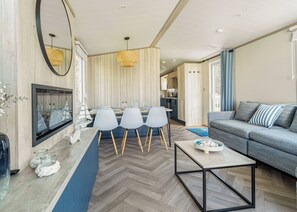 A modern living room with a sofa, a coffee table, and a dining area with chairs. - The Juniper Platinum is our signature caravan collection. (Dawlish)