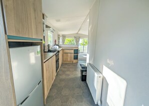 A compact kitchen with a refrigerator, stove, and wooden cabinets. - Platinum 3 bed + Deck (Longridge, Ribble Valley)