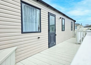 A row of mobile homes with a wooden deck and a clear sky. - Gold Caravan Sleeps 4 (Roman Bank, Skegness)