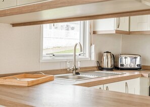 A compact kitchen with a sink, two toasters, and a window. - Kingfisher 2 Bed Hot tub (Pet) (Nr St Austell)