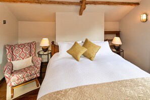 A bedroom with a bed, two nightstands, a chair, and a wooden ceiling beam. - Finest Retreats | Styles Farm Stables (Mappowder)