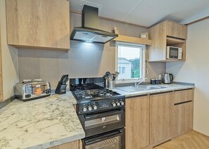 A compact kitchen with a gas stove, built-in oven, and a microwave. - 1 bedroom accommodation in Dawlish (Dawlish)