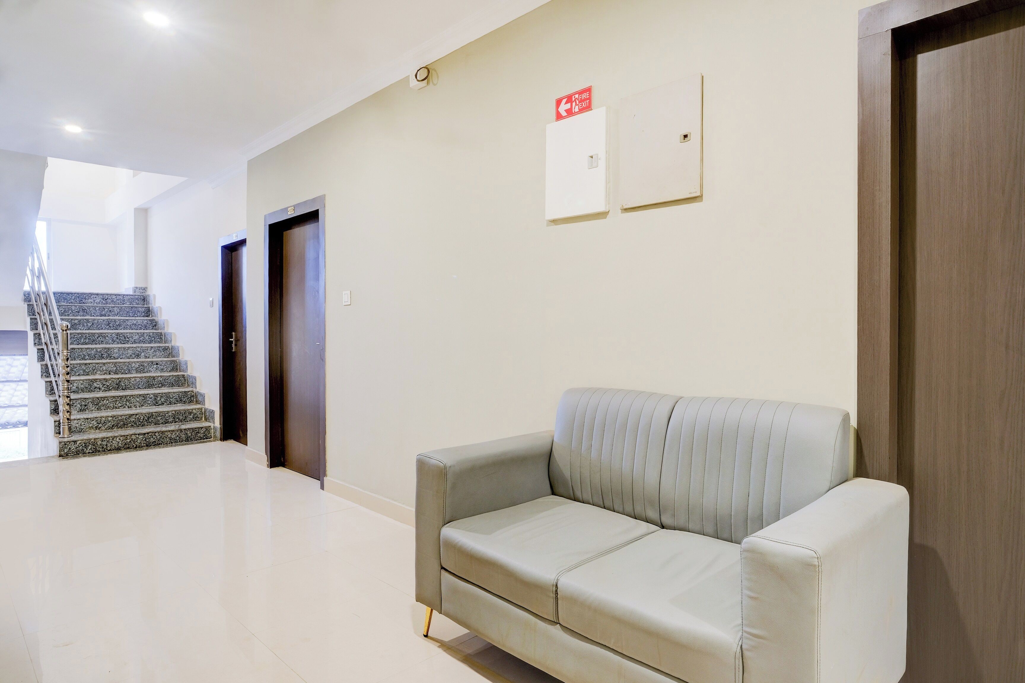 Una hall d'albergo con una scala, un divano e un segnale di uscita di sicurezza.