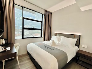 Een hotelkamer met een bed, een bureau, een stoel en een raam met gordijnen.