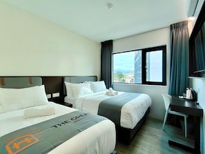 Een hotelkamer met twee bedden, een bureau, een stoel en een raam met gordijnen.