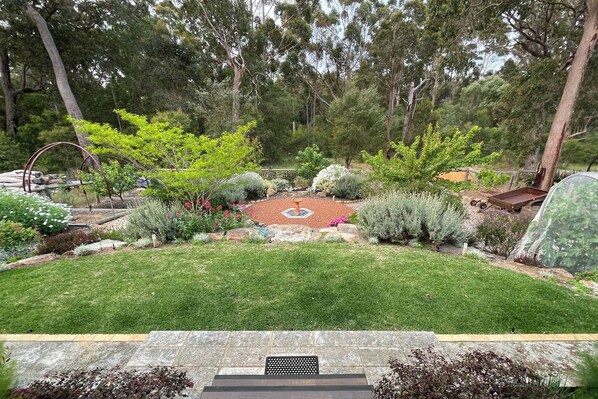 A well-maintained garden with a variety of plants and a central circular stone feature.