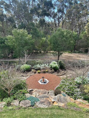 Un giardino curato con un'area circolare centrale, una fontana e diverse piante e rocce.