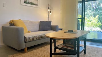 Un salon avec un canapé, une table ronde en bois, une lampe et une bibliothèque.