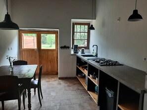 A kitchen with a wooden door, a window, a sink, and a stove. - Holiday Home 'Du Moulin' with Mountain View, Private Terrace and Wi-Fi (Pailharès)